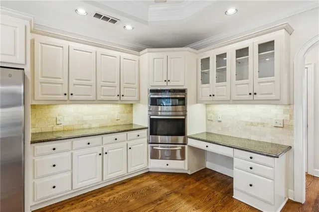 a kitchen with stainless steel appliances granite countertop a stove and white cabinets