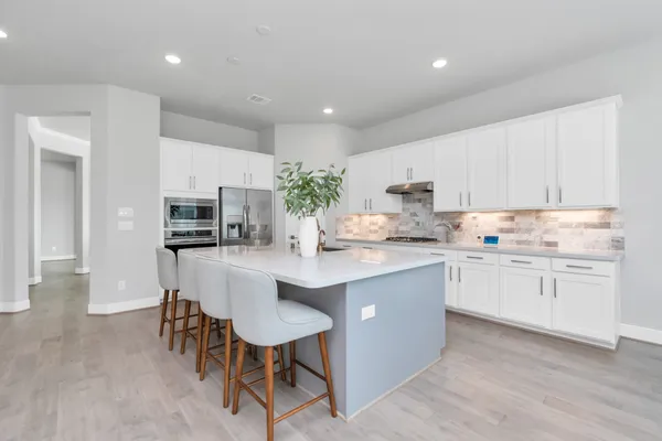 a kitchen with kitchen island granite countertop stainless steel appliances cabinets a sink and a island