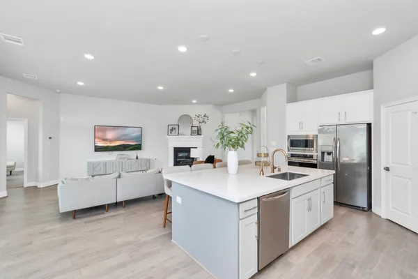 a kitchen that has a lot of white cabinets and stainless steel appliances