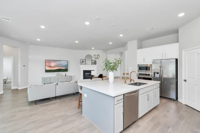 a kitchen that has a lot of white cabinets and stainless steel appliances