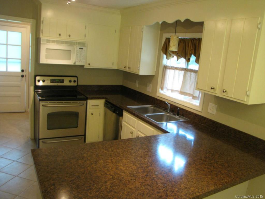 6133 Williams Road Charlotte, NC 28215 - Photo 6 of 14 a kitchen with granite countertop a stove a sink and a microwave
