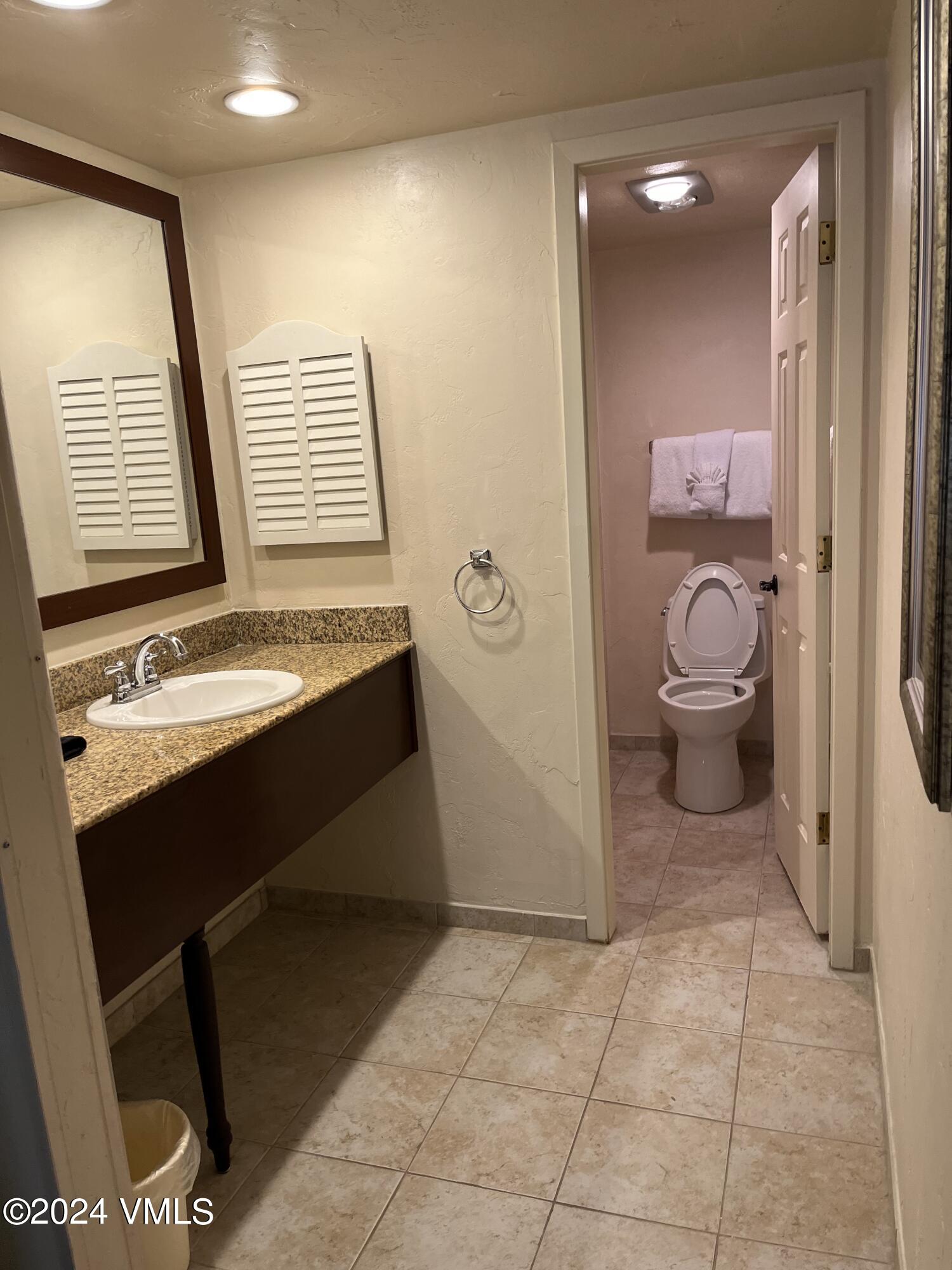 1020 Vail View Drive, Unit 330448 Vail, CO 81657 - Photo 7 of 24 a bathroom with a granite countertop toilet a sink and a mirror