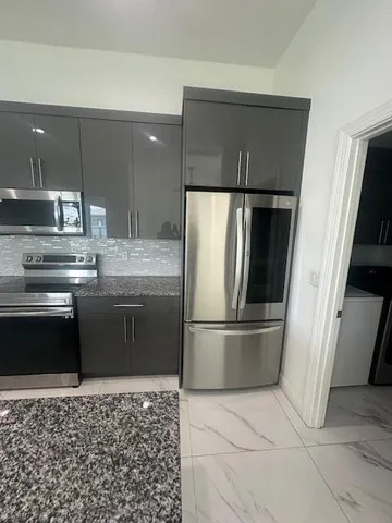 a kitchen with stainless steel appliances granite countertop a refrigerator and a stove top oven