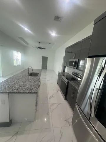 a kitchen with granite countertop a refrigerator and a sink