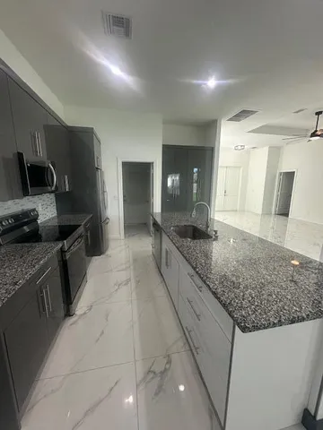 a large kitchen with kitchen island granite countertop a sink and dishwasher a stove with wooden floor