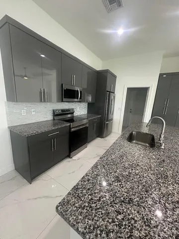 a kitchen with stainless steel appliances granite countertop a sink stove and refrigerator