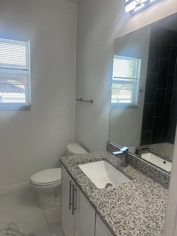a bathroom with a granite countertop sink a toilet and a mirror