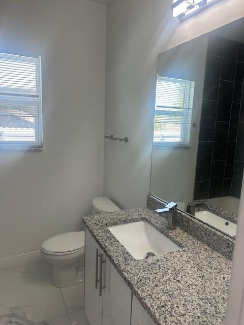 1726 Southwest California Boulevard Port St. Lucie, FL 34953 - Photo 17 of 41 a bathroom with a granite countertop sink a toilet and a mirror