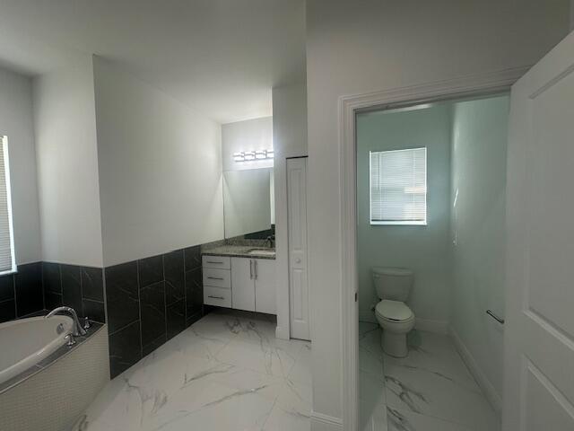 1726 Southwest California Boulevard Port St. Lucie, FL 34953 - Photo 24 of 41 a bathroom with a granite countertop sink a toilet and bathtub