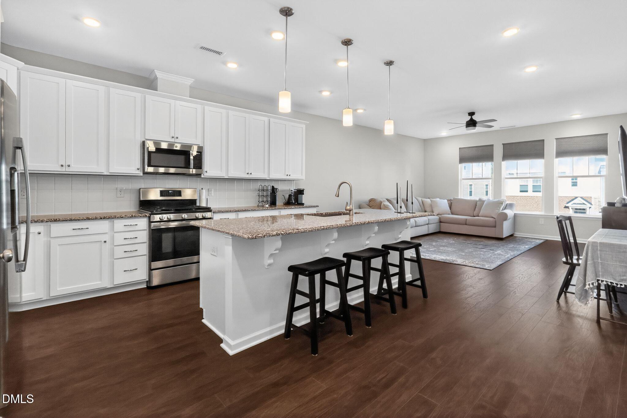 1118 Commack Drive Durham, NC 27703 - Photo 5 of 30 a kitchen with stainless steel appliances granite countertop a stove a sink a oven a dining table and chairs with wooden floor