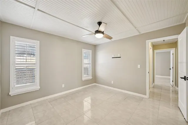 an empty room with windows and fan