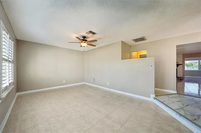 an empty room with windows and chandelier fan