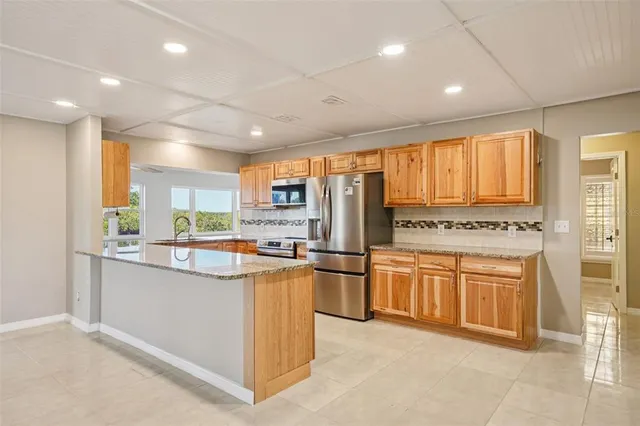 a kitchen with stainless steel appliances granite countertop a refrigerator a sink dishwasher a stove and white cabinets with wooden floor