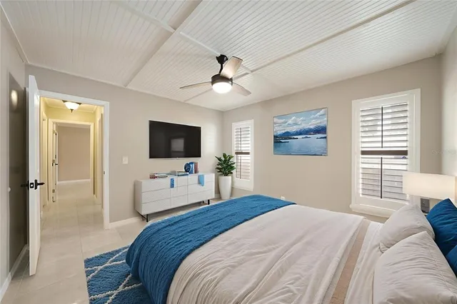 a bedroom with a bed a flat screen tv and a chandelier