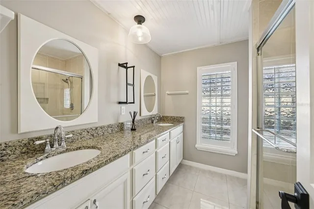 a bathroom with a granite countertop double vanity sink and a mirror