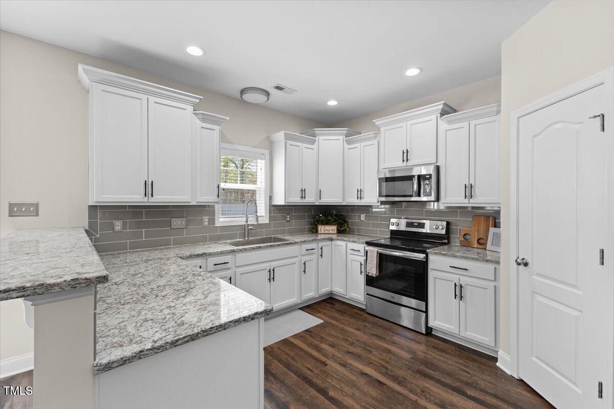 166 Old Field Loop Sanford, NC 27332 - Photo 14 of 50 a kitchen with kitchen island granite countertop white cabinets and white appliances