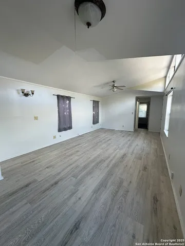 a view of a big room with wooden floor and windows