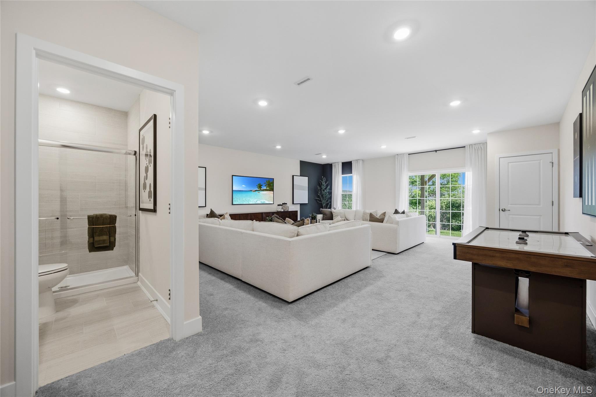 101 Pine Ridge Road Tuxedo Park, NY 10987 - Photo 21 of 26 Spacious finished walkout basement with plush gray carpeting, recessed lighting, and a sliding glass door leading to outdoor space.