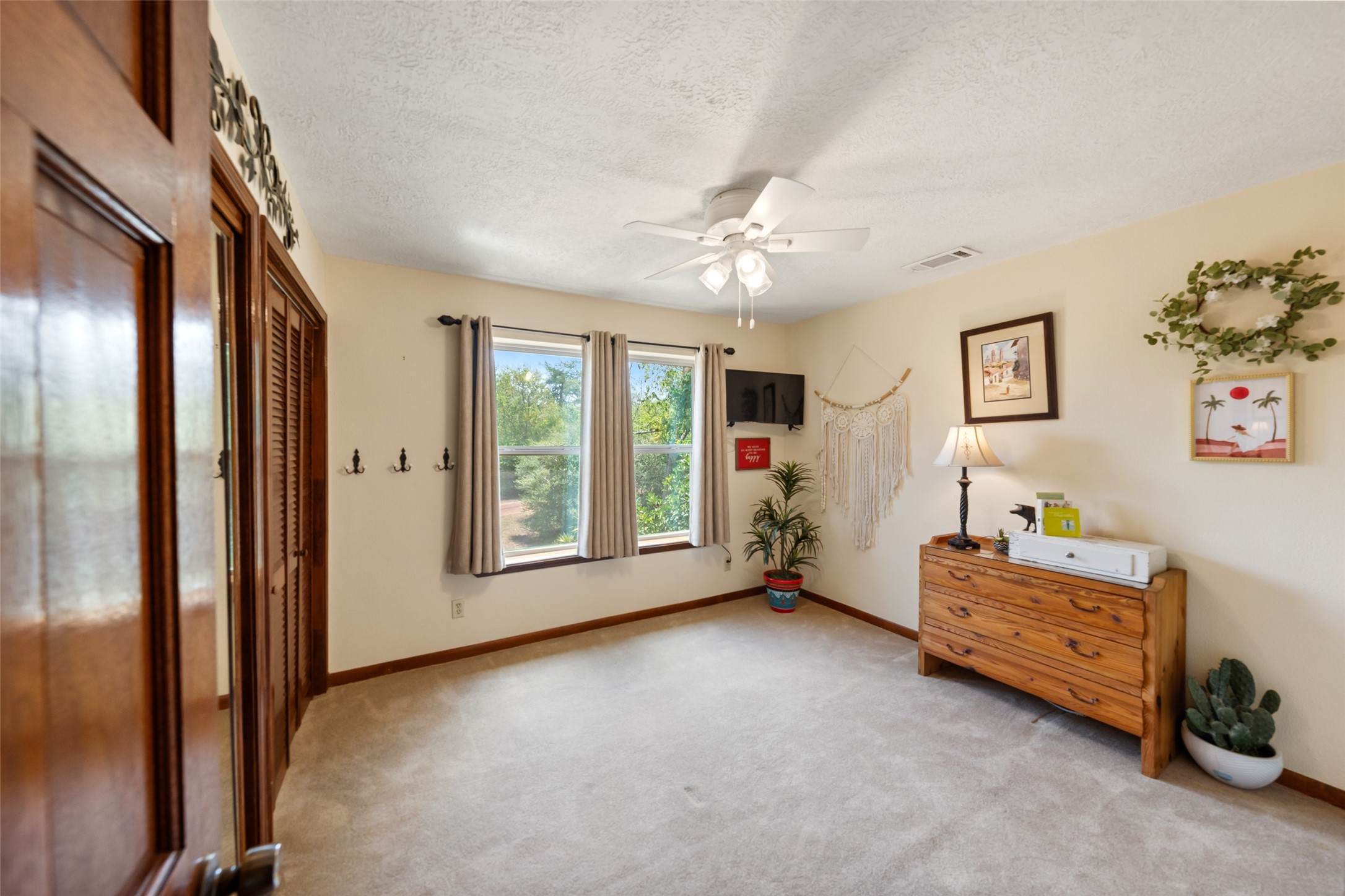25948 Nelson Road Hempstead, TX 77445 - Photo 23 of 46 Spacious bedroom featuring neutral finishes, ceiling fan, ample natural light, and large windows overlooking the surrounding greenery.