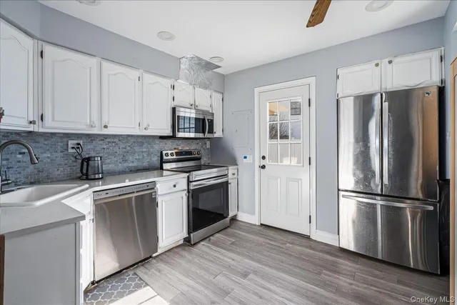 a kitchen with stainless steel appliances granite countertop a refrigerator sink and white cabinets