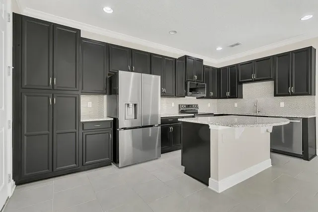 a kitchen with kitchen island a counter top space cabinets and stainless steel appliances