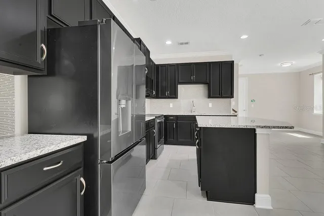 a kitchen with kitchen island granite countertop a refrigerator and a sink