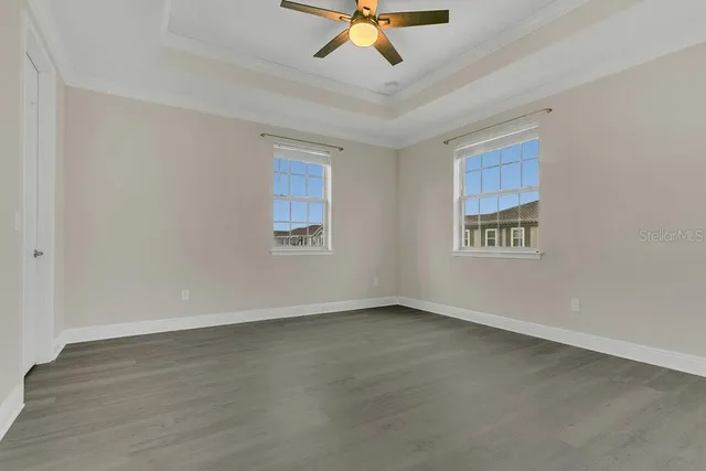 a view of an empty room with wooden floor ceiling fan