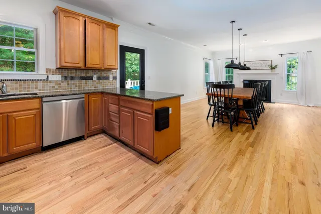 a kitchen with stainless steel appliances granite countertop wooden floors a stove top oven a sink and a granite counter tops