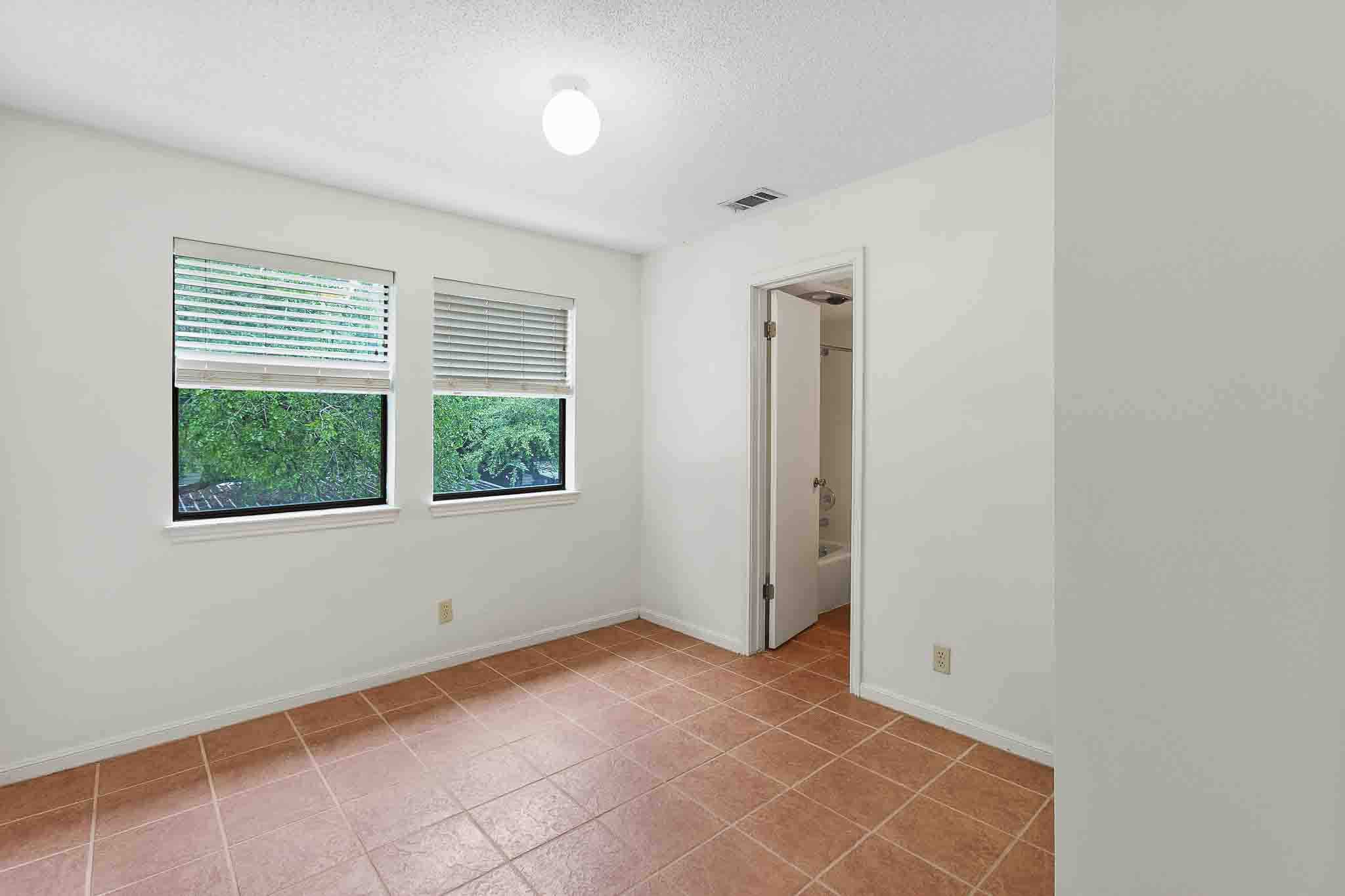 9226 Jollyville Road, Unit 132 Austin, TX 78759 - Photo 10 of 15 A quiet bedroom with durable tile flooring and a refreshing view of green foliage through twin windows.