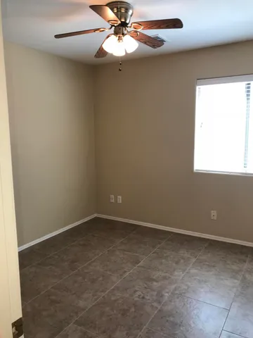 an empty room with windows and fan