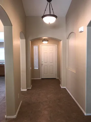an empty room with chandelier fan and windows