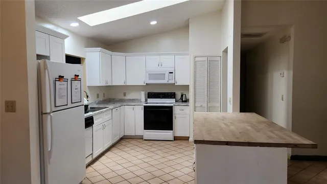 a kitchen with granite countertop white cabinets and white appliances
