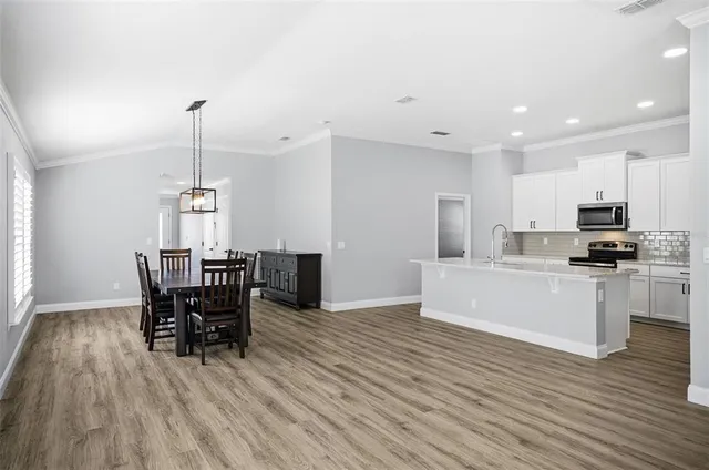 a kitchen with stainless steel appliances kitchen island granite countertop a wooden table chairs and granite counter tops