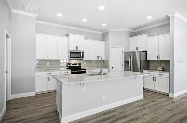 a kitchen with stainless steel appliances a refrigerator sink and white cabinets