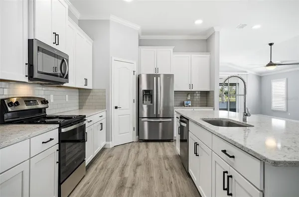 a kitchen with stainless steel appliances granite countertop a sink stove microwave and refrigerator