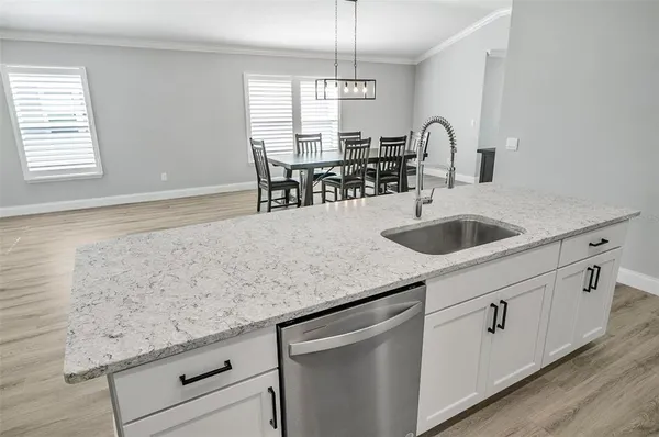 a kitchen with granite countertop a sink white cabinets and window