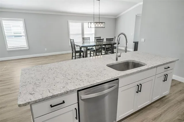 a kitchen with granite countertop a sink white cabinets and window
