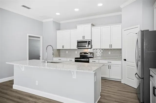 a kitchen with kitchen island a sink stainless steel appliances and cabinets