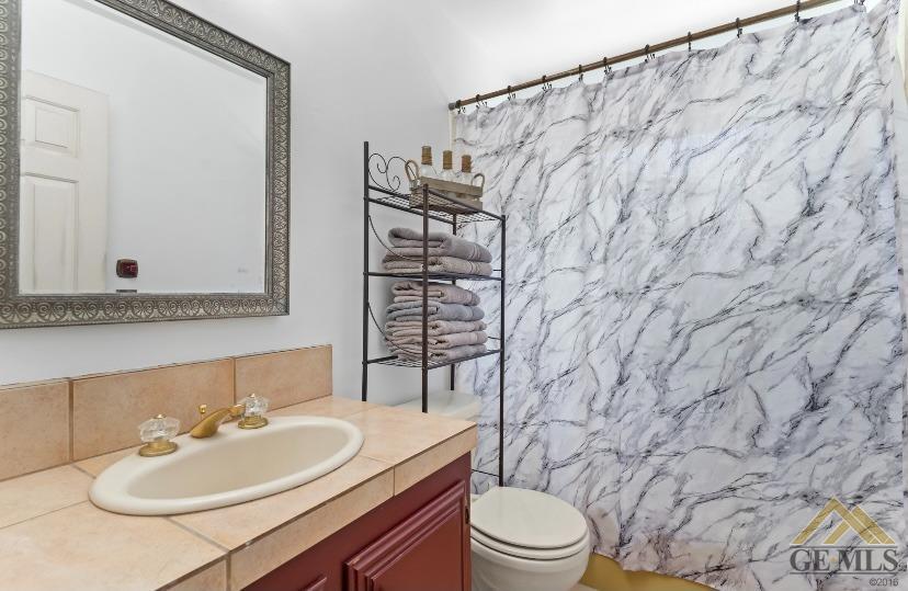 Undisclosed Address Bakersfield, CA 93309 - Photo 6 of 18 a bathroom with a sink a toilet and shower curtain