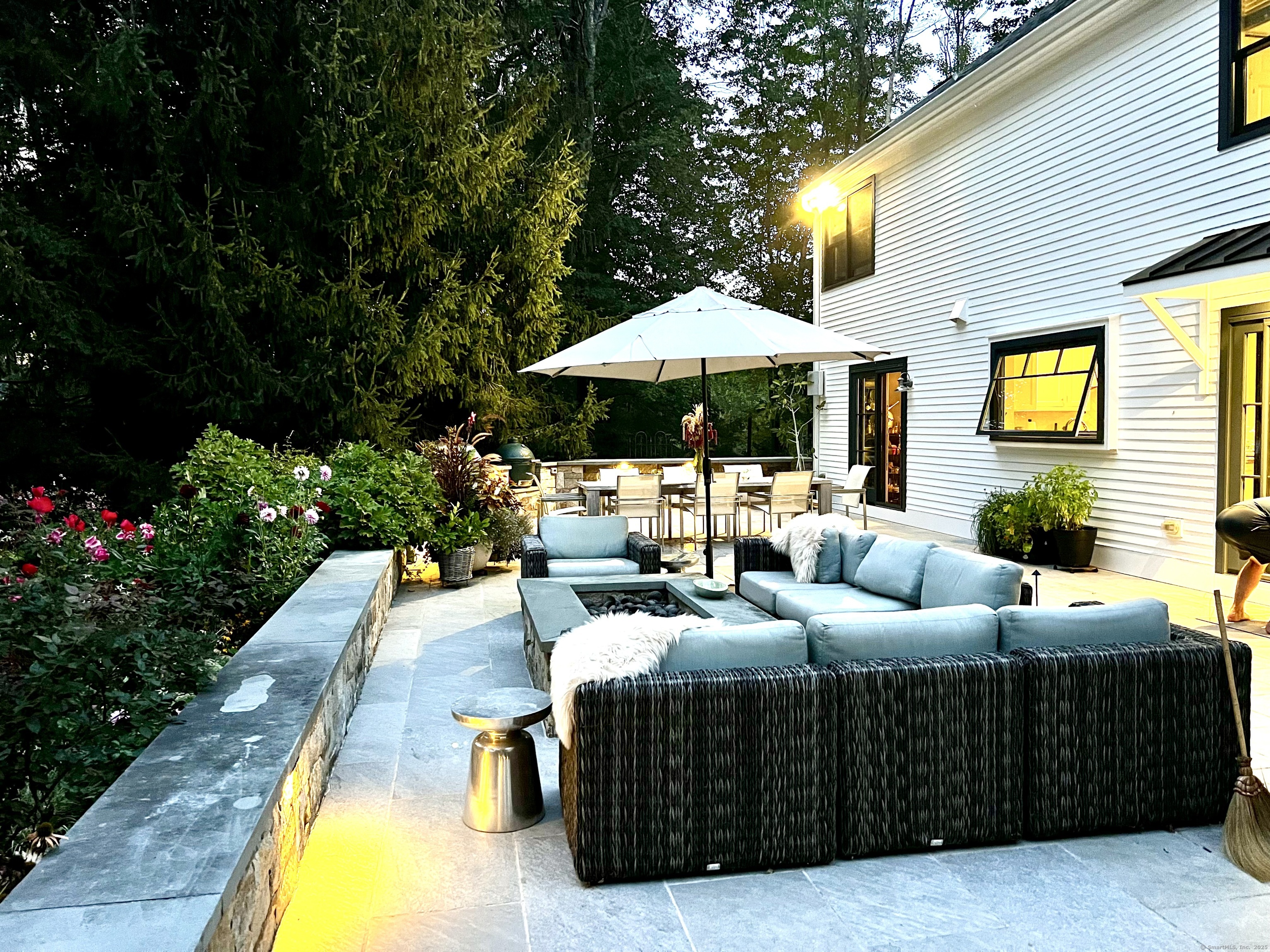 81 Graenest Ridge Road Wilton, CT 06897 - Photo 38 of 39 a view of a patio with couches table and chairs under an umbrella