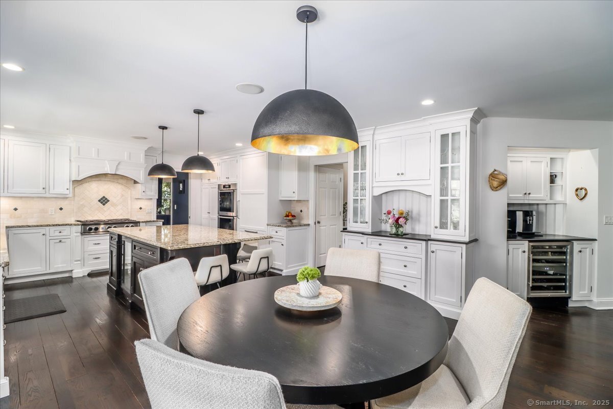 81 Graenest Ridge Road Wilton, CT 06897 - Photo 9 of 39 a kitchen with stainless steel appliances a dining table and chairs with wooden floor