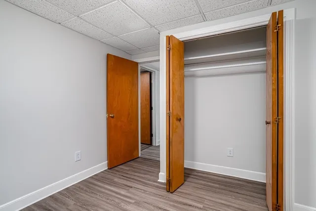 a view of an empty room with wooden floor and closet