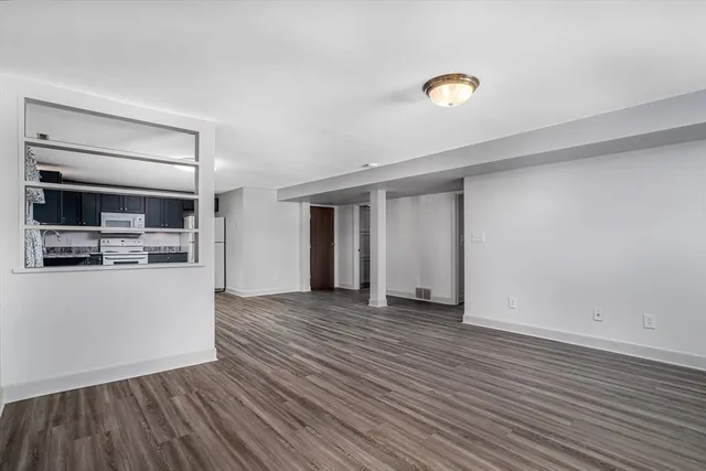 a view of a livingroom with wooden floor and kitchen space