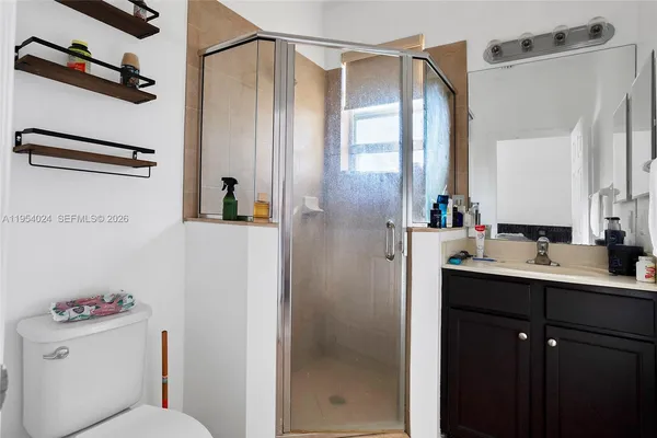 a bathroom with a shower sink vanity mirror and toilet