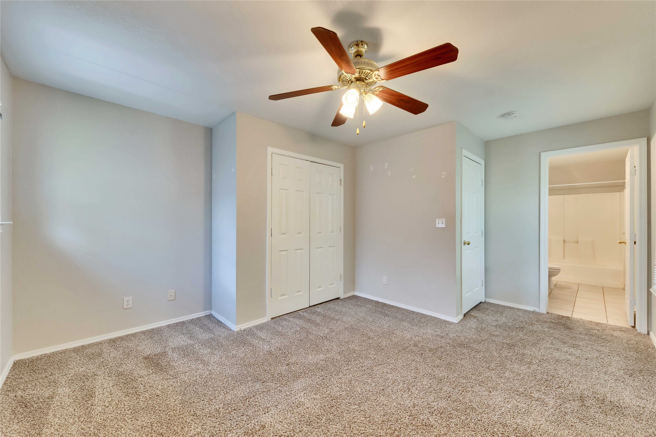 2201 East 18th Street, Unit B Austin, TX 78702 - Photo 14 of 25 A comfortable bedroom with plush carpeting features a ceiling fan and convenient closet access.