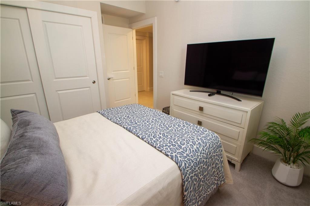 172 Indies Drive East, Unit 8102 Naples, FL 34114 - Photo 27 of 49 a bedroom with a bed and a flat screen tv