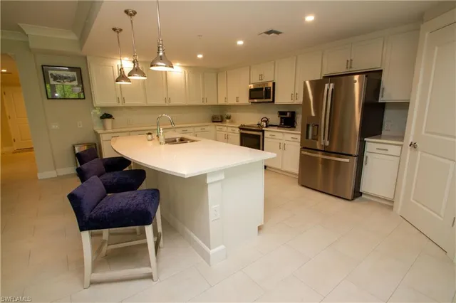 a kitchen with a refrigerator a microwave oven a sink and chairs