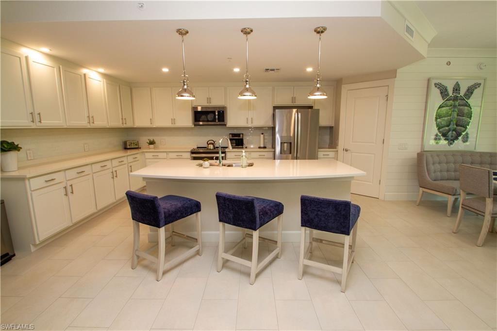 172 Indies Drive East, Unit 8102 Naples, FL 34114 - Photo 9 of 49 a kitchen with a dining table chairs and white cabinets