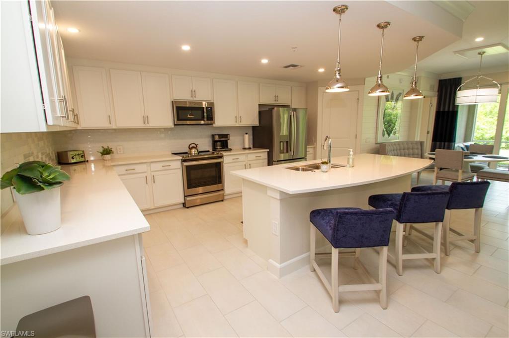 172 Indies Drive East, Unit 8102 Naples, FL 34114 - Photo 10 of 49 a kitchen with a sink a microwave and chairs