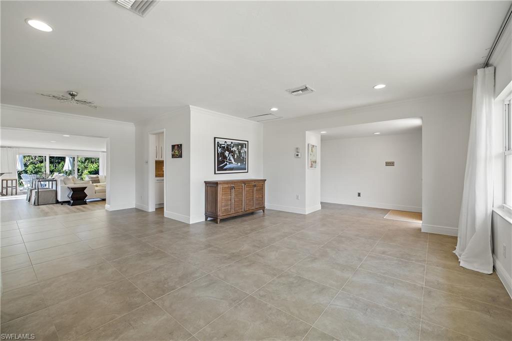 540 Rudder Road Naples, FL 34102 - Photo 18 of 37 Unfurnished living room with baseboards, visible vents, and crown molding